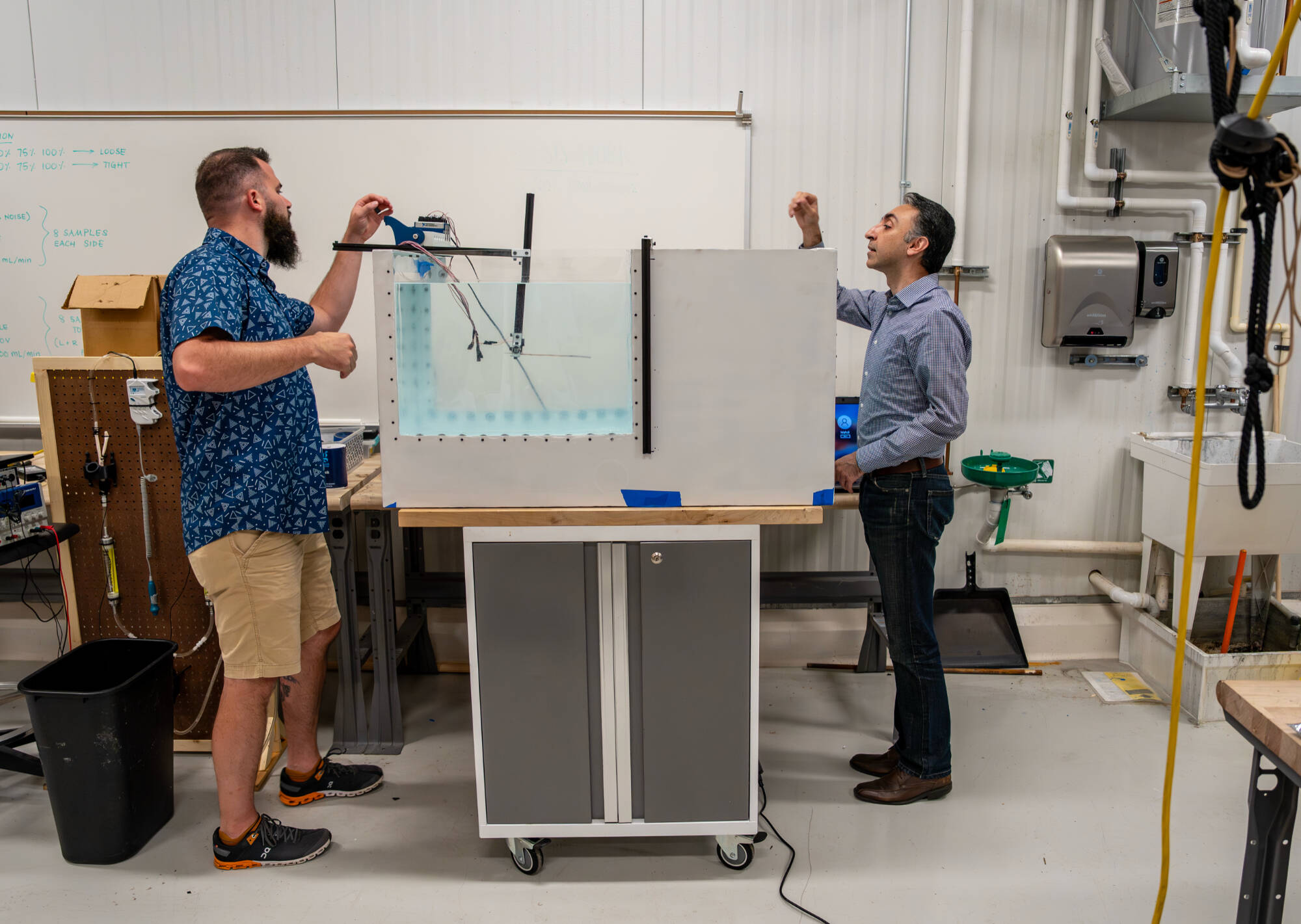 Jeremy Watkins, left, an engineering graduate student, and Farid Jafari, assistant professor of mechanical engineering, are pictured on August 6 with a 180-gallon tank Watkins built to measure the forces acting on a cantilever beam submerged in water a...
